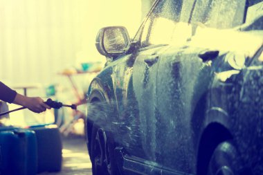 Yüksek basınçlı suyun hareket halindeki bulanık görüntüsü hareket ediyor ve araba yıkamada su sıçratıyor. Araç bakım merkezi için bulanık arkaplan. 