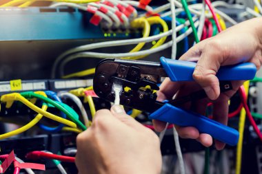 Bilgisayar odasındaki UTP kablo ve bilgisayar ağının bulanık arkaplanındaki RJ45 aracını sıkıştırarak RJ45 Connector 'a seçici odak. RJ45 konnektörünü kıstırıyorum. Bağlantı prosedürü UTP kablosu.