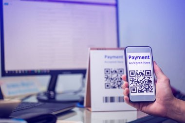 Bilgisayar ekranında bulanık Online alışveriş web sitesi ile Qr kod ödemesini taramak için akıllı telefonu tutan müşterilere seçici odak. Dijital ödeme ve online alışveriş kavramı.