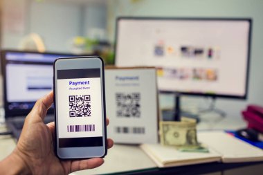 Bilgisayar ekranında bulanık Online alışveriş web sitesi ile Qr kod ödemesini taramak için akıllı telefonu tutan müşterilere seçici odak. Dijital ödeme ve online alışveriş kavramı.