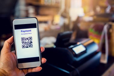 Kahve dükkanındaki kasiyer makinesiyle QR kod ödemesi taranıyor. Parasız dijital ödeme kabul edildi. Cüzdan ve nakitsiz teknoloji konsepti. 