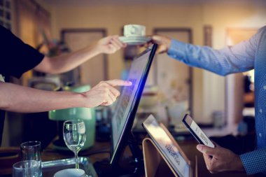 Tablet ve bulanık müşteri için seçici odak akıllı telefon taraması QR kodunu tablet üzerinde kullanarak kahve dükkanındaki tezgah barında kasiyer makinesiyle ödeme yapmak. Kabul edilen dijital ödeme para olmadan oluşturulur.