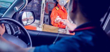 Otobanın parasını sürücüye odaklı olarak öde. Adam otoyol gişesi girişi için kasiyere para ödüyor. Yol boyunca el ödemesi ekspres geçiş ücreti. Hızlı ödeme yolu.