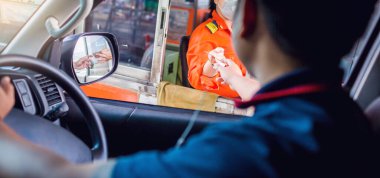 Otobanın parasını sürücüye odaklı olarak öde. Adam otoyol gişesi girişi için kasiyere para ödüyor. Yol boyunca el ödemesi ekspres geçiş ücreti. Hızlı ödeme yolu.