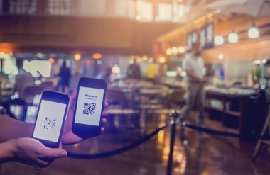 Akıllı telefondaki QR kod ödemesine seçici odak, onu taramak için bulanık akıllı telefon ve müşteriler restoranlarda yiyecek satın alarak para almadan dijital ödeme yapmayı kabul ediyor..
