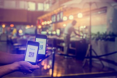 Bulanık müşteriyle etiketli QR kodunu taramak için elimizdeki akıllı telefona seçici odak, restoranlarda para olmadan dijital ödeme yapmayı kabul etmek üzere yiyecek satın almaktır. Qr kod ödeme kavramı.