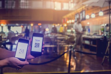 Bulanık müşteriyle etiketli QR kodunu taramak için elimizdeki akıllı telefona seçici odak, restoranlarda para olmadan dijital ödeme yapmayı kabul etmek üzere yiyecek satın almaktır. Qr kod ödeme kavramı.