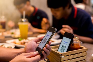 Bulanık yiyeceklerle, tatlılarla ve restoranttaki müşterilerle para almadan dijital ödeme yapılmasını kabul etmek için akıllı telefona seçici bir odaklanma. Qr kod ödeme kavramı.
