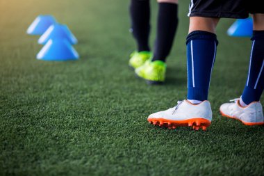 Çocuk futbolcular yeşil suni sahada bulanık koni işaretleriyle antrenmana ve oyuna başlamaya hazırlar. Futbol ya da futbol akademisi.