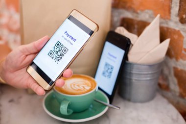 Müşteri akıllı telefonu kullanarak kahve dükkanında ya da restoranda parası olmadan dijital ücret alabilmek için QR kod etiketini başka bir akıllı üzerinde tarıyor. Qr kod ödeme kavramı.