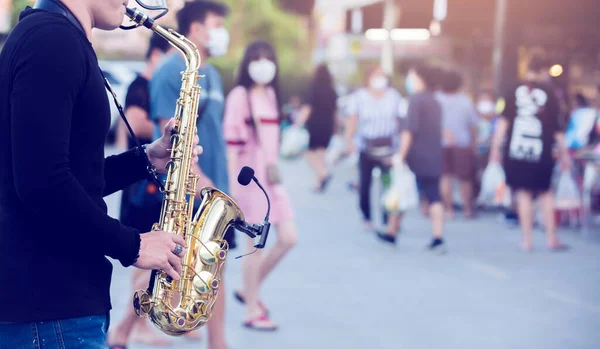 Уличный Музыкант Играет Саксофоне Носит Щит Лица Размытыми Лицами Многие — стоковое фото