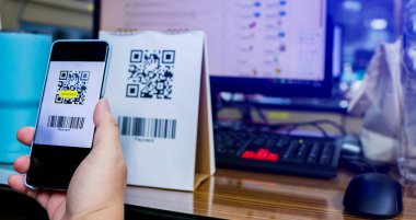 Qr kod ödemelerini ve bilgisayar ekranında bulanık online alışveriş sitesi olan barkodları taramak için akıllı telefonu tutan müşterilere seçici odaklanma. Dijital ödeme ve online alışveriş kavramı.