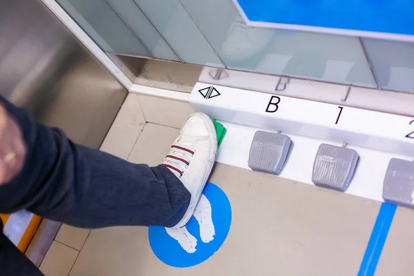 脚踏在脚踏开关上选择乘客电梯的楼层 修改载客升降机的按钮以防止结肠病毒的蔓延 Covid — 图库照片