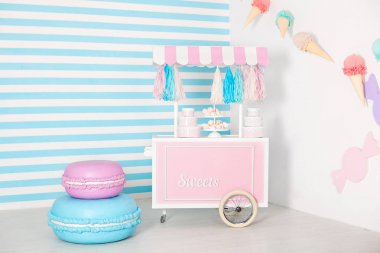 Mavi çizgili arka planlı çocuk odası. büyük macaroons, tatlılar ve marshmallows ile şeker tezgahı fotoğraf bölgesi. dondurma ile arabası. Doğum günü için dekore edilmiş oda. Candy Bar ile Sepeti. 