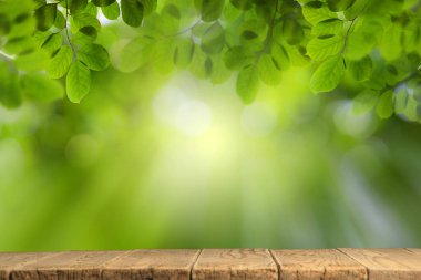 Bokeh arkaplan ve yazı için güneş ışığı olan boş ahşap masa, şablon maketi ve ürün görüntüsü. yeşil doğa ve ekoloji kavramı.
