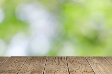 Bokeh arkaplanı olan boş tahta masa ve metin için fotokopi alanı olan güneş ışığı, ürün gösterimi için şablon oluşturun. yeşil doğa kavramı.