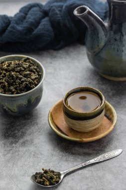 Çimento masasında kaşık içinde kuru yapraklı sıcak yeşil çay. Sağlıklı içki konsepti.