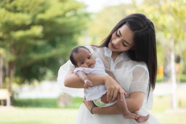 Genç Asyalı anneler ya da bekar anneler gülümsüyor ve yeni doğmuş bebekler taşıyorlar. Aile aktiviteleri yapıyor ve parkta dinleniyor. Bir eş ve annenin çocuk ve aile yetiştirmedeki görevleri hakkında.