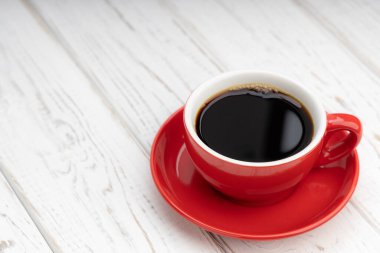 Kırmızı kahve fincanı, beyaz masa üzerinde dumanla fotokopi alanı ile birlikte..