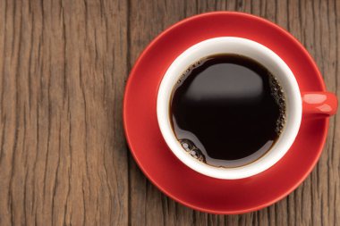 Kırmızı kahve bardağının üst görüntüsü ahşap masada fotokopi alanı ile birlikte..