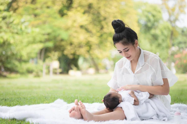 Beautiful Asian young mother  or single mom with new born baby girl are doing activities and relaxing in the park. concept of duties of wife and mother in raising children and family.