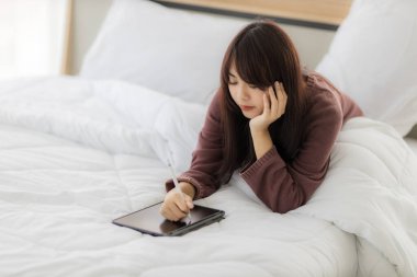 Çalışmak için tablet kullanan Asyalı kadın, eğitim, e-ticaret, yatağında sosyal medya. Corovavirus covid-19, evde kal, iş formu ev kavramı.