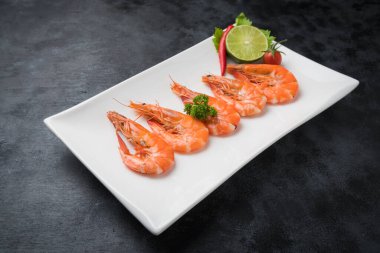 Siyah masada beyaz tabakta kaynamış karides..