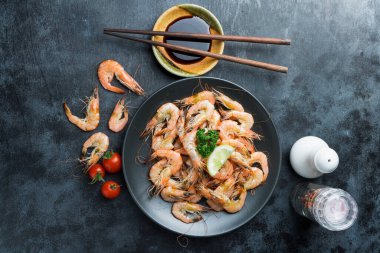 Siyah tabakta kaynamış karides ve siyah masada sos..