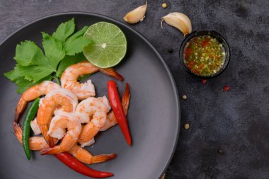 Siyah tabakta karides ve siyah masada deniz ürünleri sosu..