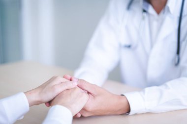 Kadın doktor erkek hastaların elini tutuyor..