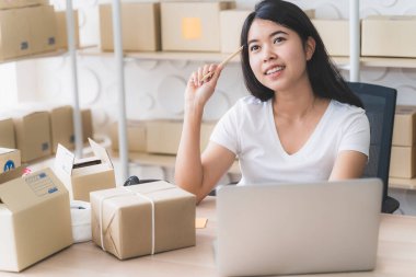 Evde çalışan Asyalı serbest kadın ve internet üzerinden küçük işletme girişimcisi KME 'yi kuruyor. Genç bayan sipariş sayısını kontrol etmek için dizüstü bilgisayar kullanıyor..