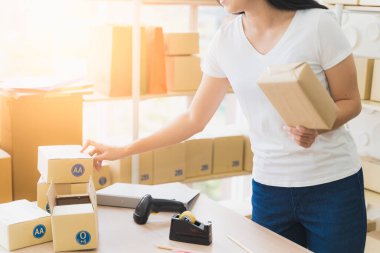 Evde çalışan Asyalı serbest kadın ve internet üzerinden küçük işletme girişimcisi KME 'yi kuruyor. Kadın teslimatı hazırlamak için paket kutusu hazırlıyor..