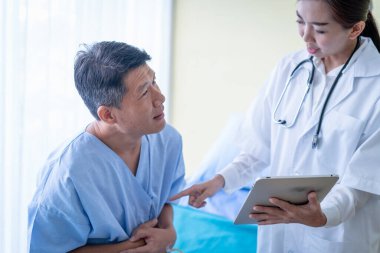 Kadın doktorlar tabletten hasta bir erkek hastaya bir şey açıklıyorlar..