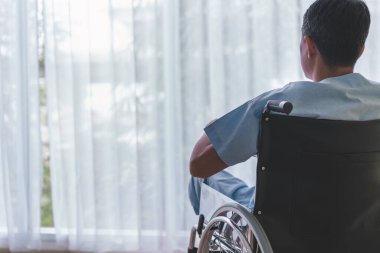 Erkek hastalar tekerlekli sandalyede yalnız oturuyor..