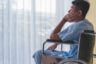 Erkek hastalar tekerlekli sandalyede yalnız oturuyor..