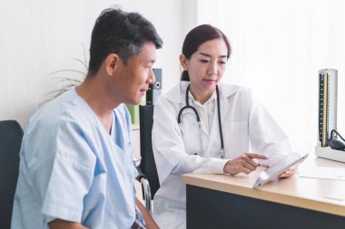 Kadın doktorlar tabletten hasta bir erkek hastaya bir şey açıklıyorlar..