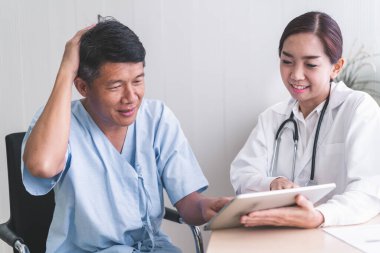 Kadın doktorlar tabletten hasta bir erkek hastaya bir şey açıklıyorlar..