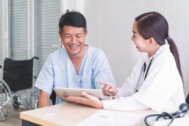 Kadın doktorlar tabletten hasta bir erkek hastaya bir şey açıklıyorlar..