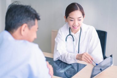 Kadın doktorlar tabletten hasta bir erkek hastaya bir şey açıklıyorlar..