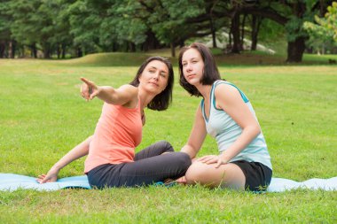 Parkta, parmağıyla işaret eden yaşlı bir kadın tarafından iki kadın etkinlik düzenleniyor..