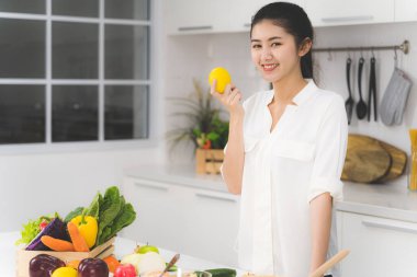 Asyalı güzel bir kadının portresi gülümsüyor ve ellerinde limon gösteriyor. Sağlıklı gıda konsepti