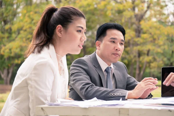 Asian businessman and woman in garden.