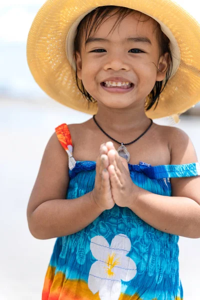 ハワイのドレスを着てビーチで藁帽子をかぶっているかわいいタイの女の子の肖像画 小さな女の子の笑顔とSawasdeeはタイの国家文化です — ストック写真