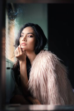Seksi Asyalı kadın portresi sigara içiyor.