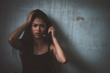 Genç Asyalı kadının sade portresi eski odada telefonla konuşuyor. Sosyal sorunlar, suç ve uyuşturucu kavramı.