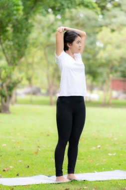 Genç kadın parkta yoga yapıyor..