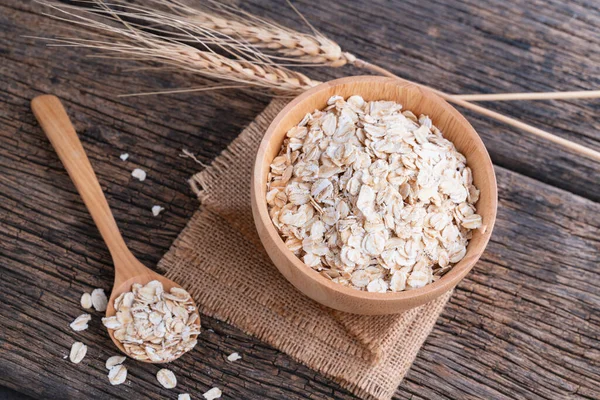 Oat flakes in wooden bowl and spoon on wooden table. Oatmeal, Oats - Food, Oat Flake.