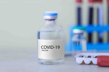 Masada bir şişe koronavirüs aşısı var. Coronavirus aşısı COVID-19 'un geliştirilmesi ve yaratılması. Coronavirus aşısına karşı mücadele aşısı.