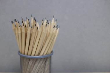 Birçok kalem çimento duvar arka planına karşı küçük bir sepete yerleştirilir. okul konseptine geri dön.