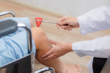 Yakın çekim doktoru, hastanede tekerlekli sandalyede oturan bir kadın hastanın dizinde kemik eklem inceleme cihazı kullanıyor..